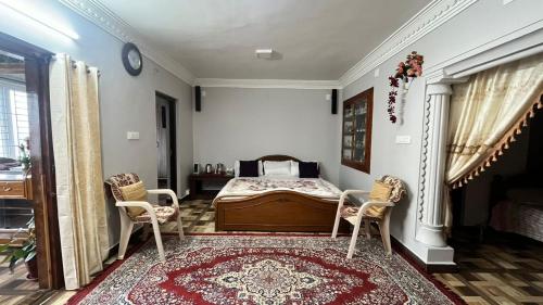 a bedroom with a bed and two chairs and a rug at Chill@hill in Ooty