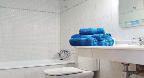 a bathroom with blue towels and a sink and a toilet at Appartement Mar y golf in Pedreguer
