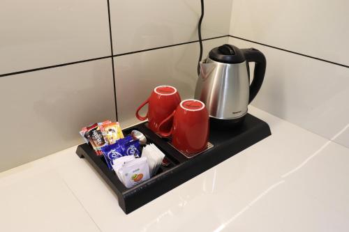 a tray with a coffee pot and two red mugs at LUXIE INN MALABAR in Perintalmanna