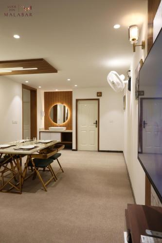a conference room with a table and a kitchen at LUXIE INN MALABAR in Perintalmanna