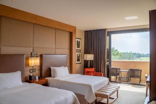 a hotel room with two beds and a balcony at VOGO Abu Dhabi Golf Resort & Spa Formerly The Westin Abu Dhabi Golf Resort & Spa in Abu Dhabi