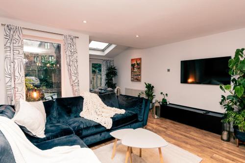 sala de estar con sofá negro y TV en Beautiful West Didsbury 4BR Home, en Mánchester