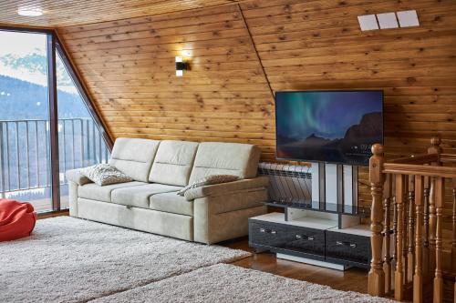 ein Wohnzimmer mit einem Sofa und einem Flachbild-TV in der Unterkunft Karakol Resort in Karakol