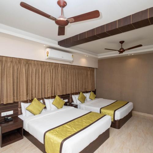 a hotel room with two beds and a ceiling fan at Hotel Central Plaza in Siliguri