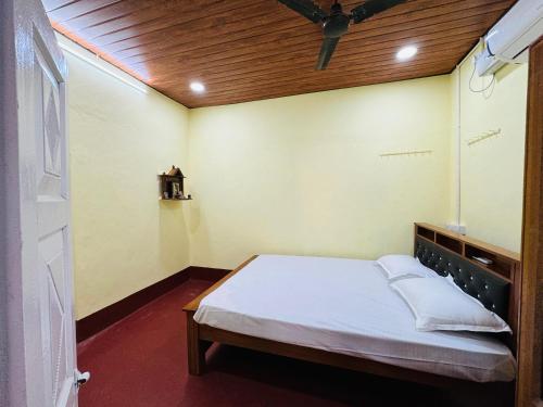 um pequeno quarto com uma cama com teto de madeira em Payal Nivas beach cottage em Padubidri