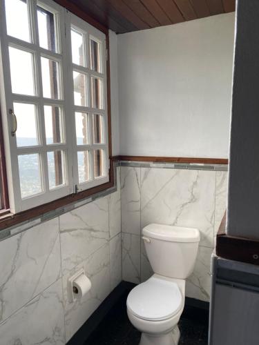 a bathroom with a white toilet and a window at Tranquility Estate in Kingston