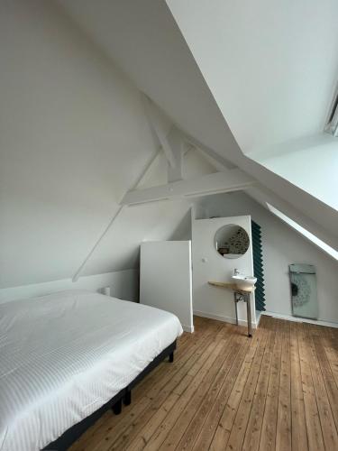 une chambre avec un lit blanc et un parquet dans l'établissement La Maison du Pays Coutançais, à Gouville-sur-Mer