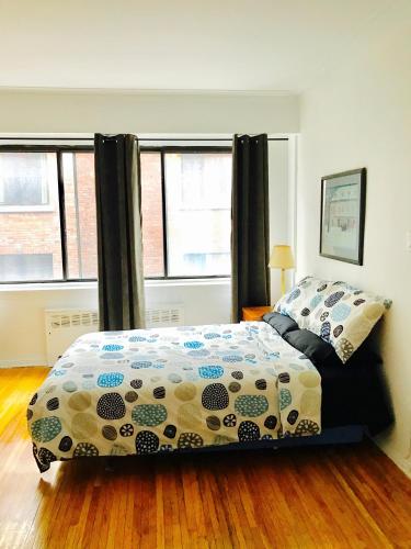 a bedroom with a bed and two windows at Stylish Montreal Apartment: Comfortable Stay in the Golden Square Mile in Montreal