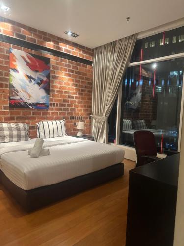 um quarto com uma cama e uma parede de tijolos em Soho Suites KLCC By Inam Suites em Kuala Lumpur