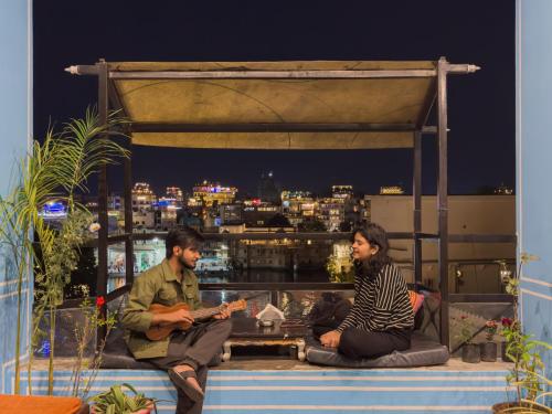 a man and woman sitting on the ledge of a building at Madpackers Udaipur in Udaipur