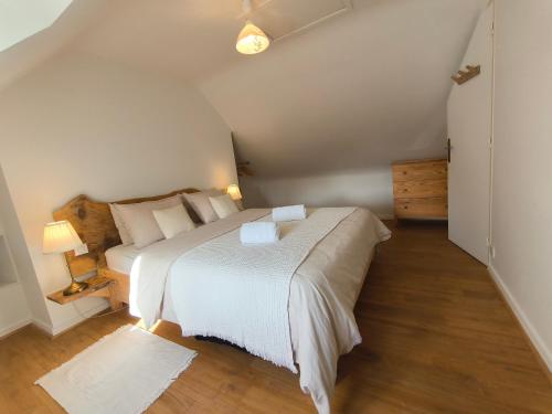 a bedroom with a white bed and a wooden floor at La Ferme de Penanguer in Loctudy