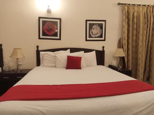 a bedroom with a large white bed with a red blanket at Herfa INN Hotel Lahore in Lahore