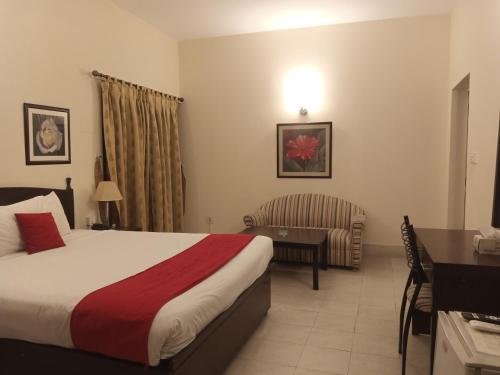 a hotel room with a bed and a desk and a chair at Herfa INN Hotel Lahore in Lahore