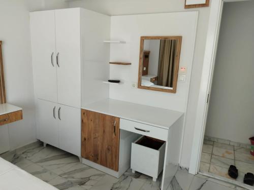 a bathroom with white cabinets and a mirror at ALİBABAM APART OTEL in Kuşadası