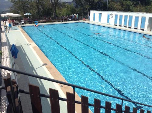 - une grande piscine bleue avec des personnes dans l'établissement La Corte Bonomini, à Neviano degli Arduini