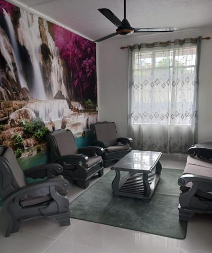 a living room with chairs and a table and a painting at An&Sy Family House in Surinam