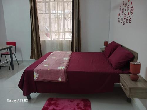 a bedroom with a purple bed with a table and a window at An&Sy Family House in Surinam