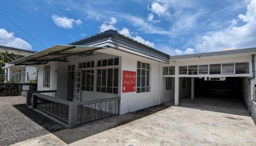 un edificio blanco con un letrero rojo. en An&Sy Family House, en Surinam