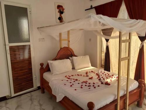 Cassandra Beach Resort في نونغوي: غرفة نوم مع سرير مع بتلات ورد حمراء عليه