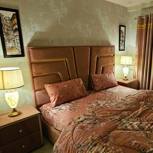a bedroom with a bed with a wooden headboard and two lamps at 1 Bed Luxury Apartment in Lahore