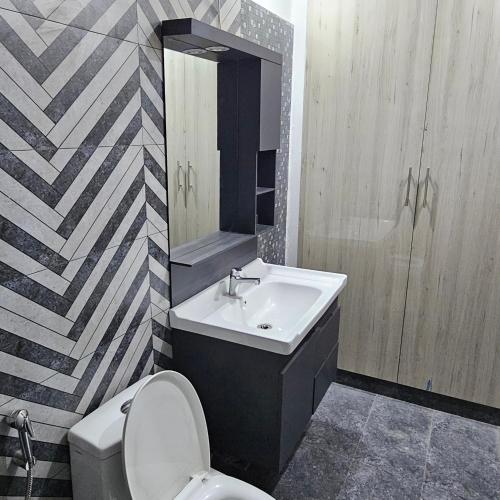 a bathroom with a sink and a toilet and a mirror at 1 Bed Luxury Apartment in Lahore