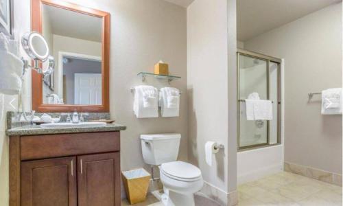 a bathroom with a toilet and a sink and a mirror at Tahiti Village in Las Vegas