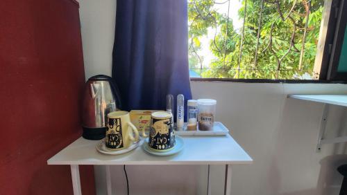 a small table with cups on it with a window at Comfy and Spacious room, close to the Royal Park Rajapruek in Chiang Mai