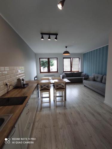a kitchen and living room with a table and chairs at Apartament Przy Latarni in Krynica Morska