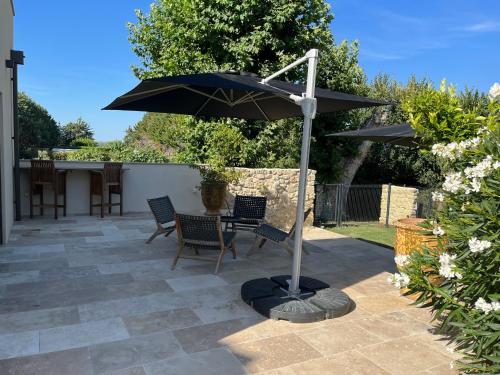 a patio with two chairs and an umbrella at Domaine de La Franquette by Bridget & Pascal - Piscine Chauffée & SPA in Caderousse