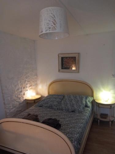 - une chambre avec un lit et deux lampes de chaque côté dans l'établissement La P'tite Maison, à Jonquières-et-Saint-Vincent