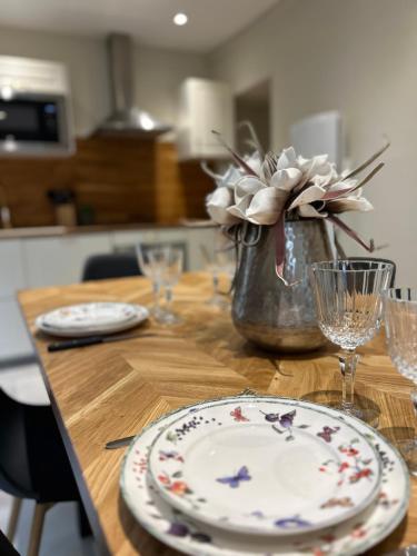 une table en bois avec des assiettes et un vase avec des fleurs dans l'établissement Maison Grandjean, à Bligny-lès-Beaune