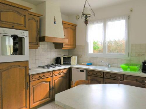 une cuisine avec des armoires en bois et un comptoir dans l'établissement Maison 3* avec jardin, wifi, à 400m de la plage à Pleumeur-Bodou - FR-1-368-286, à Pleumeur-Bodou