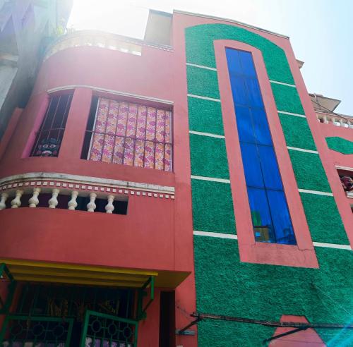 a red and green building with blue windows at Blue Waves HomeStay in Pondicherry