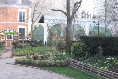 un jardin avec des girafes et des fleurs devant un bâtiment dans l'établissement APPARTEMENT PORTE CHAMPERRET, à Levallois-Perret