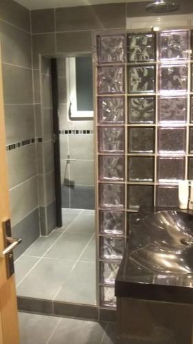 La salle de bains est pourvue d'une armoire en verre avec des bouteilles de vin. dans l'établissement APPARTEMENT PORTE CHAMPERRET, à Levallois-Perret