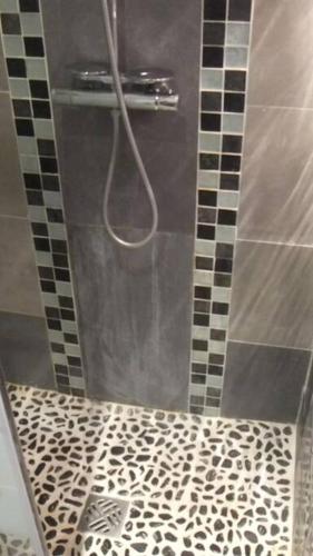 a shower with a black and white tiled floor at APPARTEMENT PORTE CHAMPERRET in Levallois-Perret