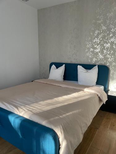 - un lit bleu avec des draps et des oreillers blancs dans l'établissement Maison de ville, à Vitry-sur-Seine