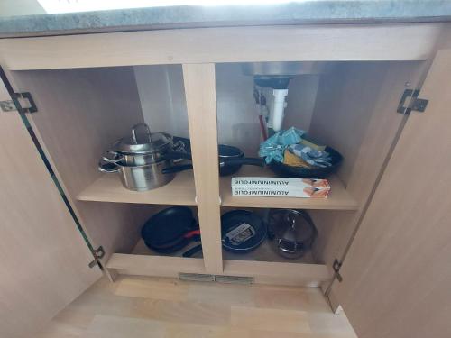 a cupboard with a shelf with pots and pans at Perenhof 6 in Oostvoorne