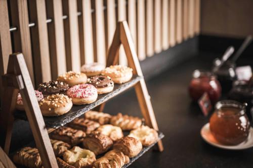 a display of different types of donuts on a shelf at Sporthotel Bachmann in Gargellen
