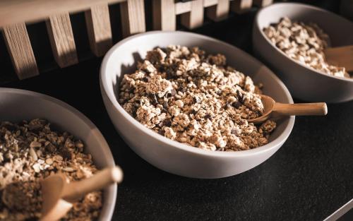 a group of four bowls of food with wooden spoons at Sporthotel Bachmann in Gargellen