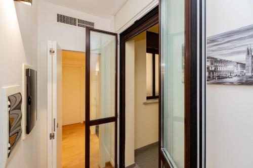 a glass door in a hallway with a painting on the wall at PREMUDA20 Milan Elegant Apartment in Milan