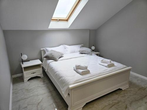 a bedroom with a large white bed with a skylight at 4You Apartment in Baia Mare