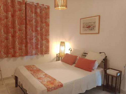 Schlafzimmer mit einem Bett mit weißer Bettwäsche und roten Kissen in der Unterkunft Ti Kaz citron in Sainte-Rose