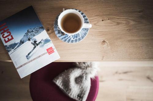 a table with a cup of coffee and a magazine at Sporthotel Bachmann in Gargellen