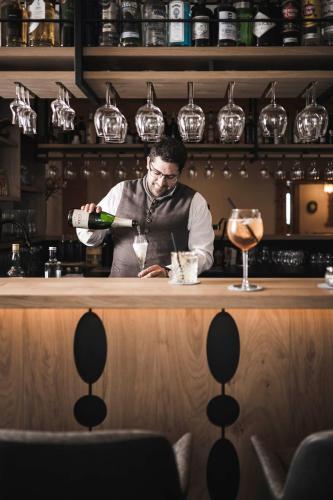 a man pouring a bottle of wine at a bar at Sporthotel Bachmann in Gargellen