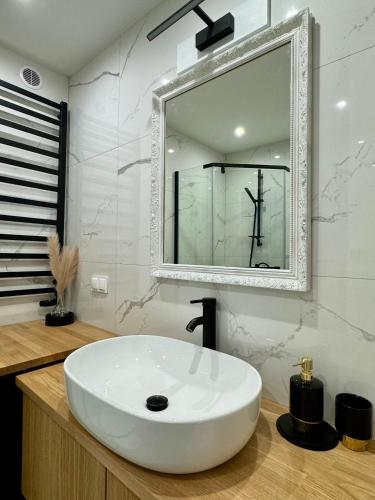a bathroom with a white sink and a mirror at Apartamenty Kowalska III in Kościerzyna