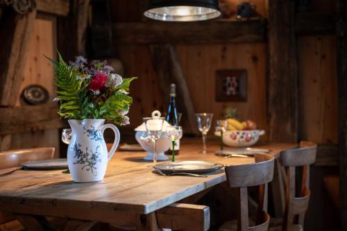 a wooden table with a vase of flowers on it at La Grange d'Hannah - gîte & chambre d’hôtes de charme in Orbey
