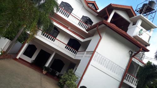 a white house with a balcony and a palm tree at Nothern Residence in Jaffna