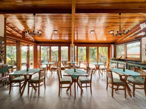 a dining room with tables and chairs and windows at Pousada Gardenian in São Roque