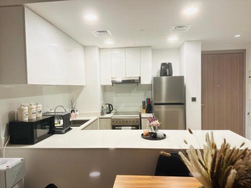 a kitchen with white counters and a refrigerator at Modern Sanctuary W/ Pool & Gym access in Sharjah